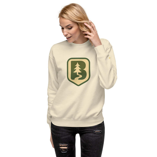 Woman wearing 70s Boise Unisex Sweatshirt in cream with forest logo, ribbed crew neck and cuffs, paired with ripped black jeans
